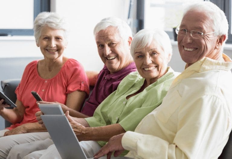 Four board members delightedly using self-managed condo association software on mobile phones and laptop for efficient community management