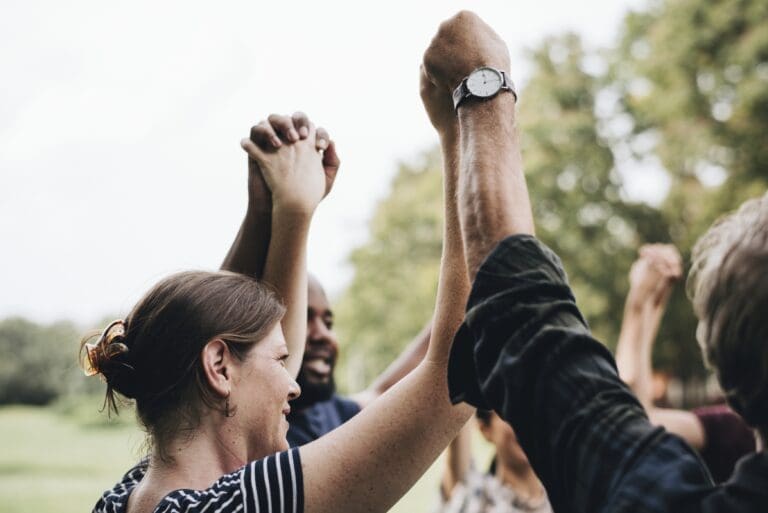 Happy diverse people holding hands in the park
