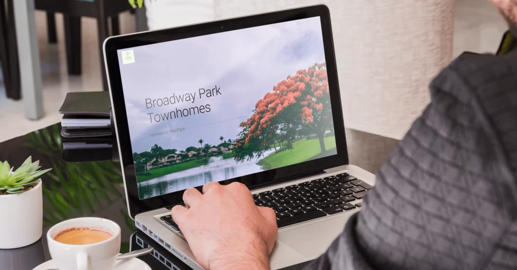 5 Simple Strategies To Reduce Maintenance Costs in your HOA 3 hoa website - image of a woman from behind looking at a laptop with a broadway parks townhomes website