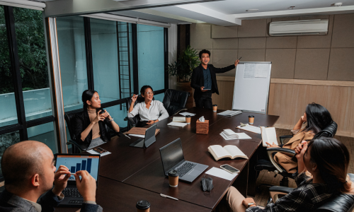 A diverse group of professionals discussing ideas and collaborating in a well-lit meeting room.