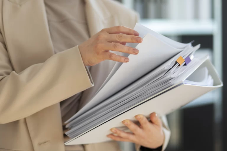 woman holding a neat stack of papers, attentively reviewing a list of HOA violations