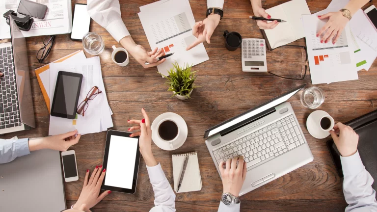 Board members in a table having an HOA board communications meeting, they have their computers and notes in the table.