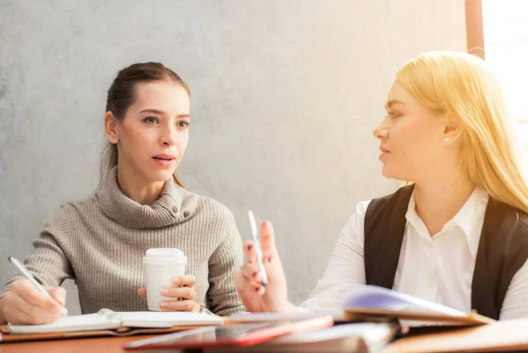 Two women sitting down reviewing questions to ask the HOA