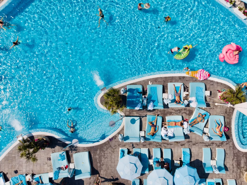 An HOA pool used by families with many blue sun loungers and colored floats