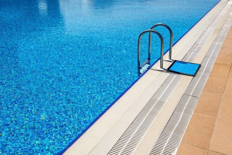 Outdoor hotel swimming pool with blue tiles and ladder